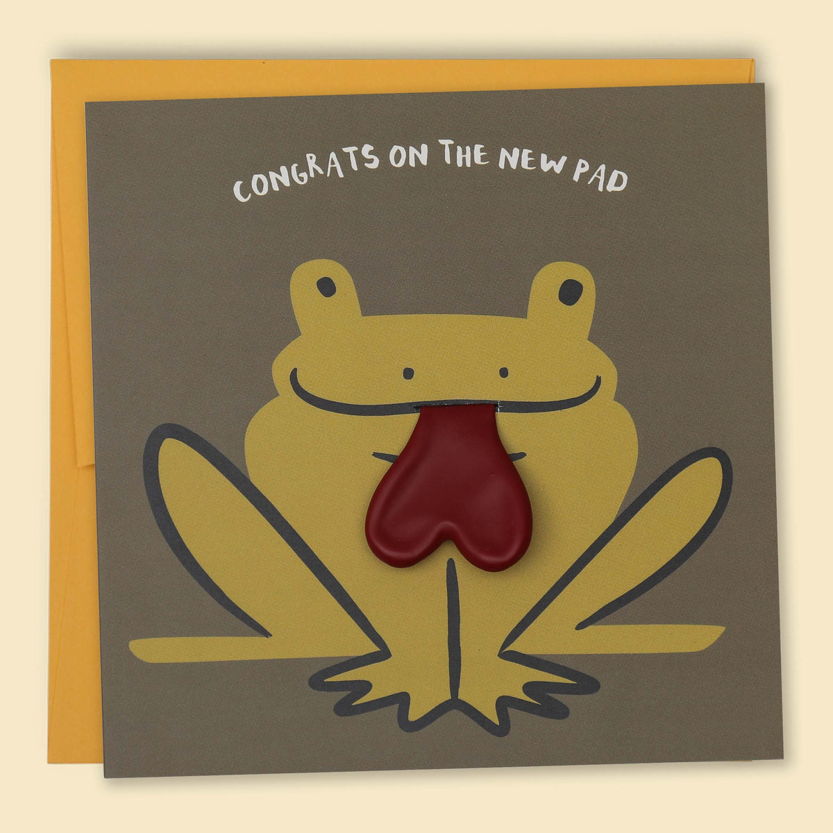 A greeting card with a cartoon frog design, with the text 'CONGRATS ON THE NEW PAD' across the top. The frog has a red heart balloon for a tongue — Australian-made greeting card by Papernest