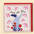 A greeting card with a hand-drawn illustration by Constanza Goeppinger of a woman with outstretched arms among flowers and birds, with the text 'And she flew' written at the top. Australian-made greeting card by Papernest.