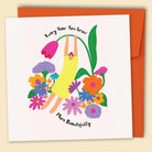 A greeting card with an illustration by Constanza Goeppinger of a person swinging on a flower stem with multiple colorful flowers around, and the text 'Every Year You Grow More Beautifully'. Australian-made greeting card by Papernest.