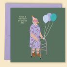 An illustrated greeting card by Constanza Goeppinger featuring a humorous image of an older person wearing a party hat holding a walking frame with balloons attached featuring the words 'Have a wheelie awesome day'. Australian-made greeting card by Papernest.