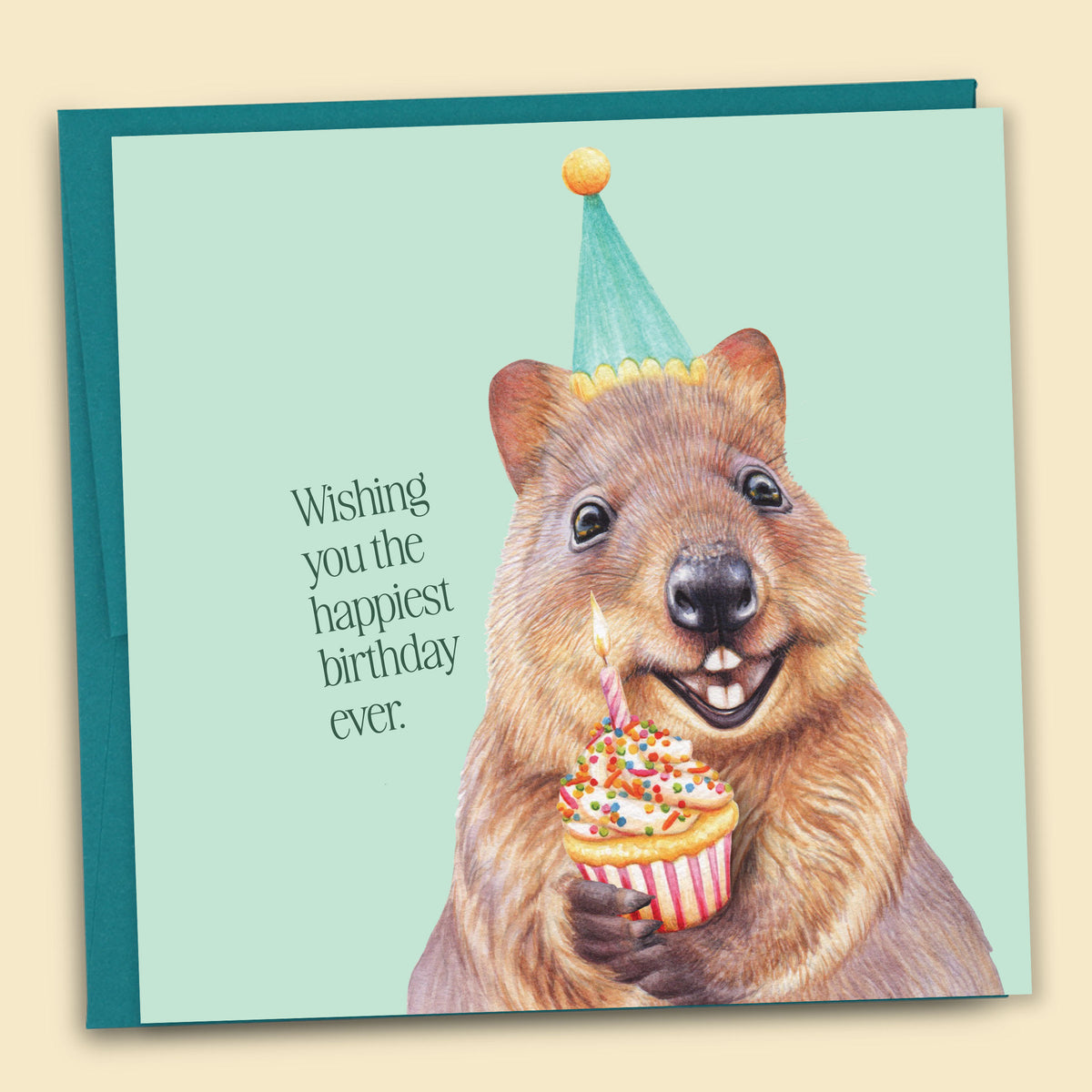 Greeting card with a quokka wearing a party hat and holding a cupcake on a mint background. Front of card says, "Wishing you the happiest birthday ever."