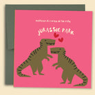 Greeting card with a playful illustration of two dinosaurs on a pink background, with the text 'MARRIAGE IS A WALK IN THE PARK' and 'JURASSIC PARK'. Australian-made greeting card by Papernest.