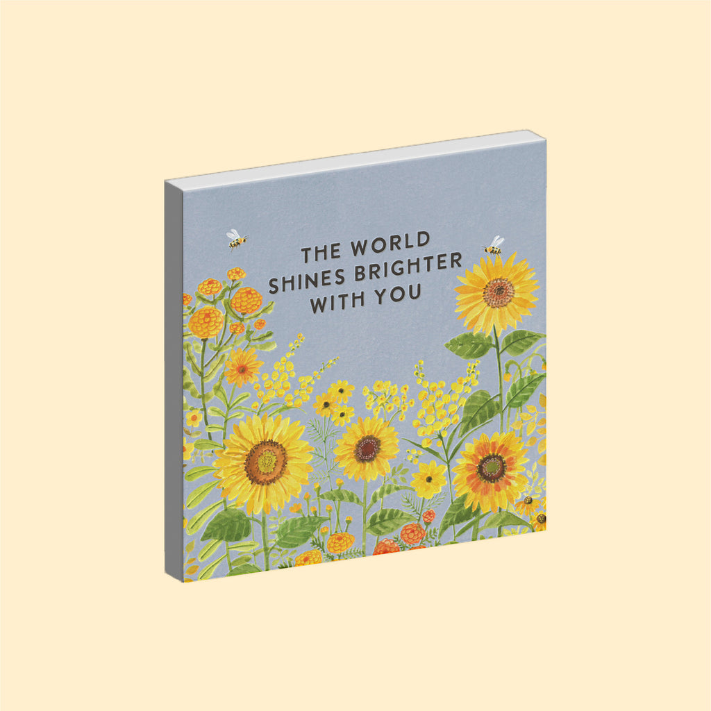 Inspirational ceramic art tile magnet with watercolour illustration of Sunflowers and a blue sky, reading The World Shines Brighter With You