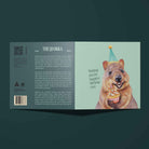 Greeting card with a quokka wearing a party hat and holding a cupcake on a mint background. Front of card says, "Wishing you the happiest birthday ever."