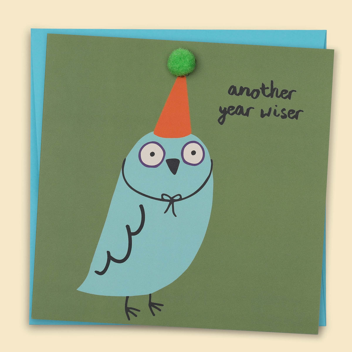 A blue bird wearing a party hat with  small green pom-pom. and the text 'Another Year Wiser' — Australian-made greeting card by Papernest