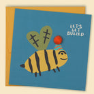 An illustration of a bee wearing a party hat with a pom pom detail and the text 'Let's get buzzed' — Australian-made greeting card by Papernest