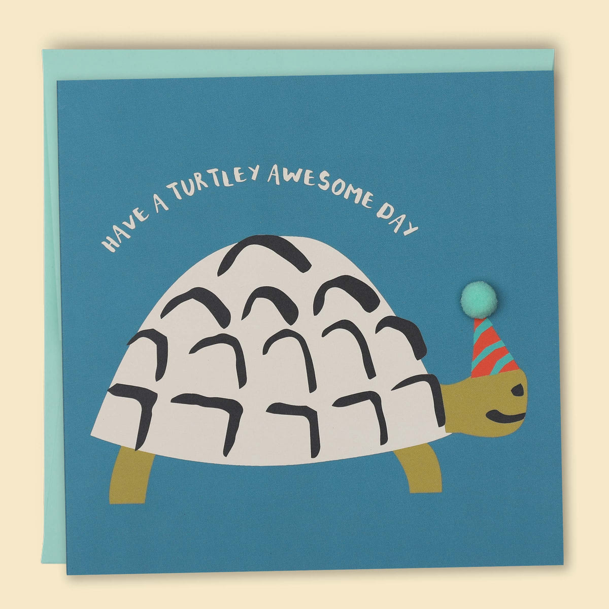 Greeting card with an illustration of a turtle wearing a party hat and balloon, with the text 'Have a Turtley AWESOME DAY!' The card is also decorated with a pom-pom detail  — Australian-made greeting card by Papernest